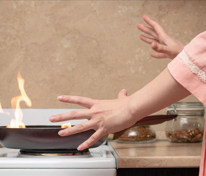Shocked woman and fire on frying pan on home kitchen concept.