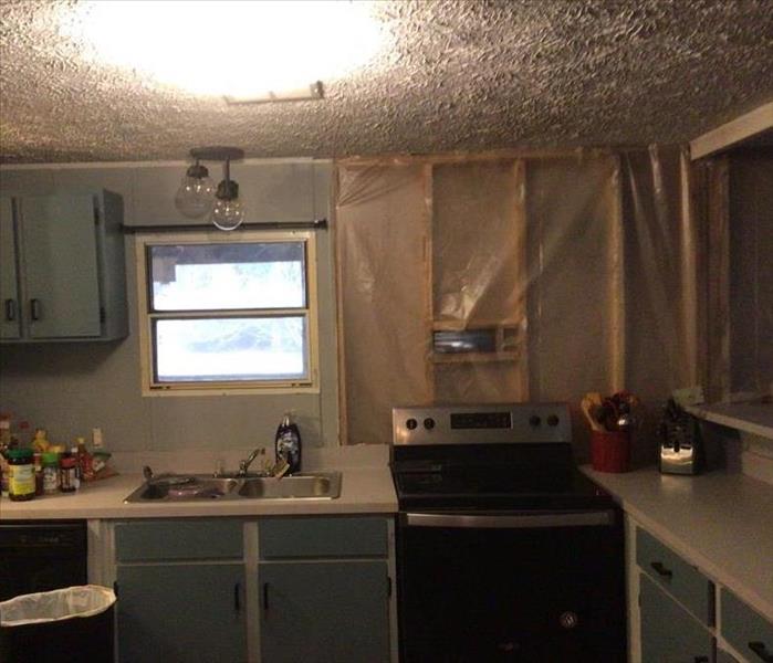A kitchen, an oven, and exposed wood due to the cabinets being pulled out