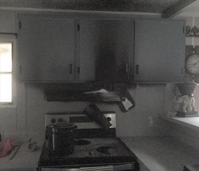 A kitchen, oven, and cabinets that are black due to smoke and fire